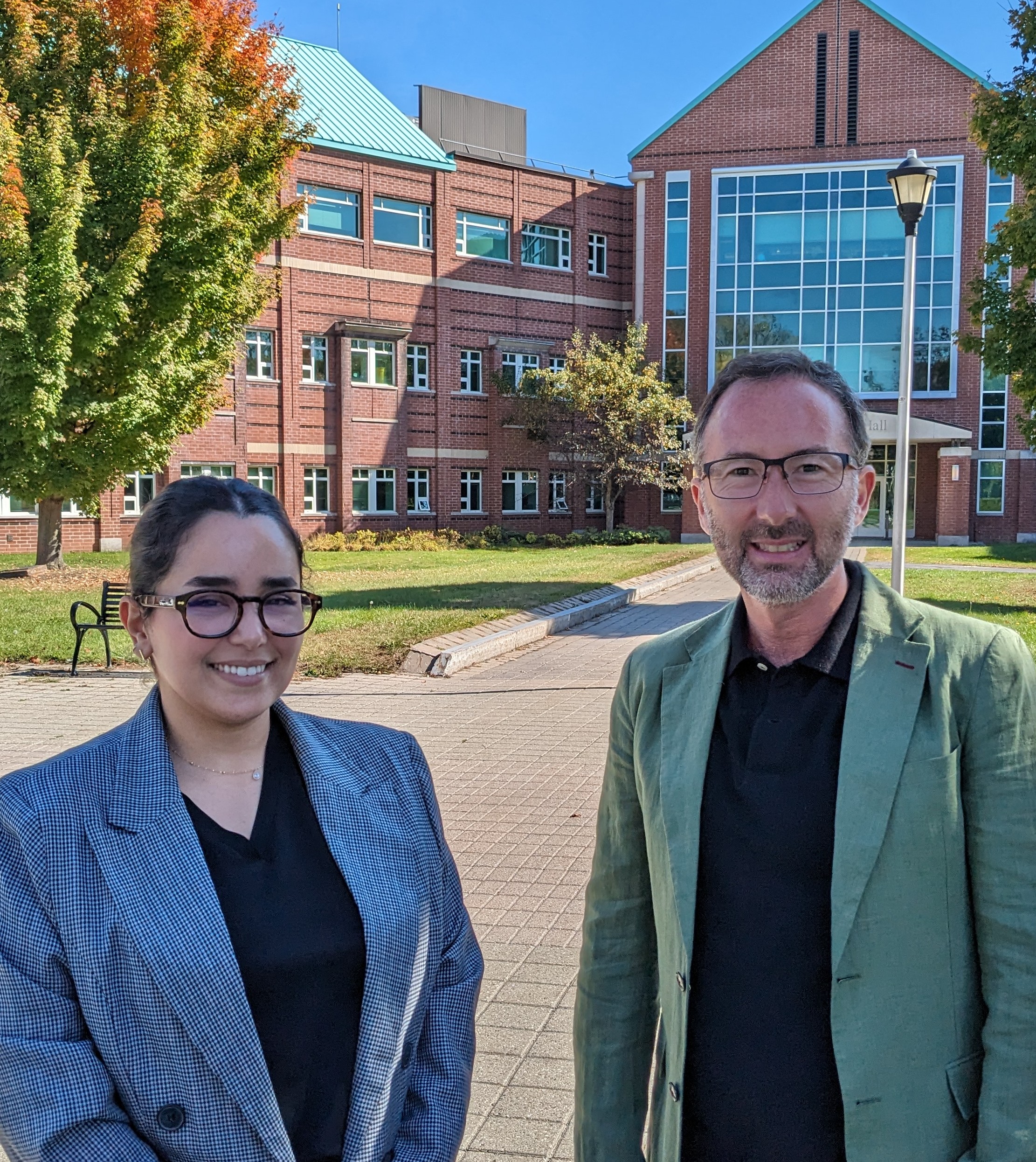 Imane Magrez and Christian Felzensztein stand in front of B.H. Snell Hall on Clarkson's Collins Hill Campus