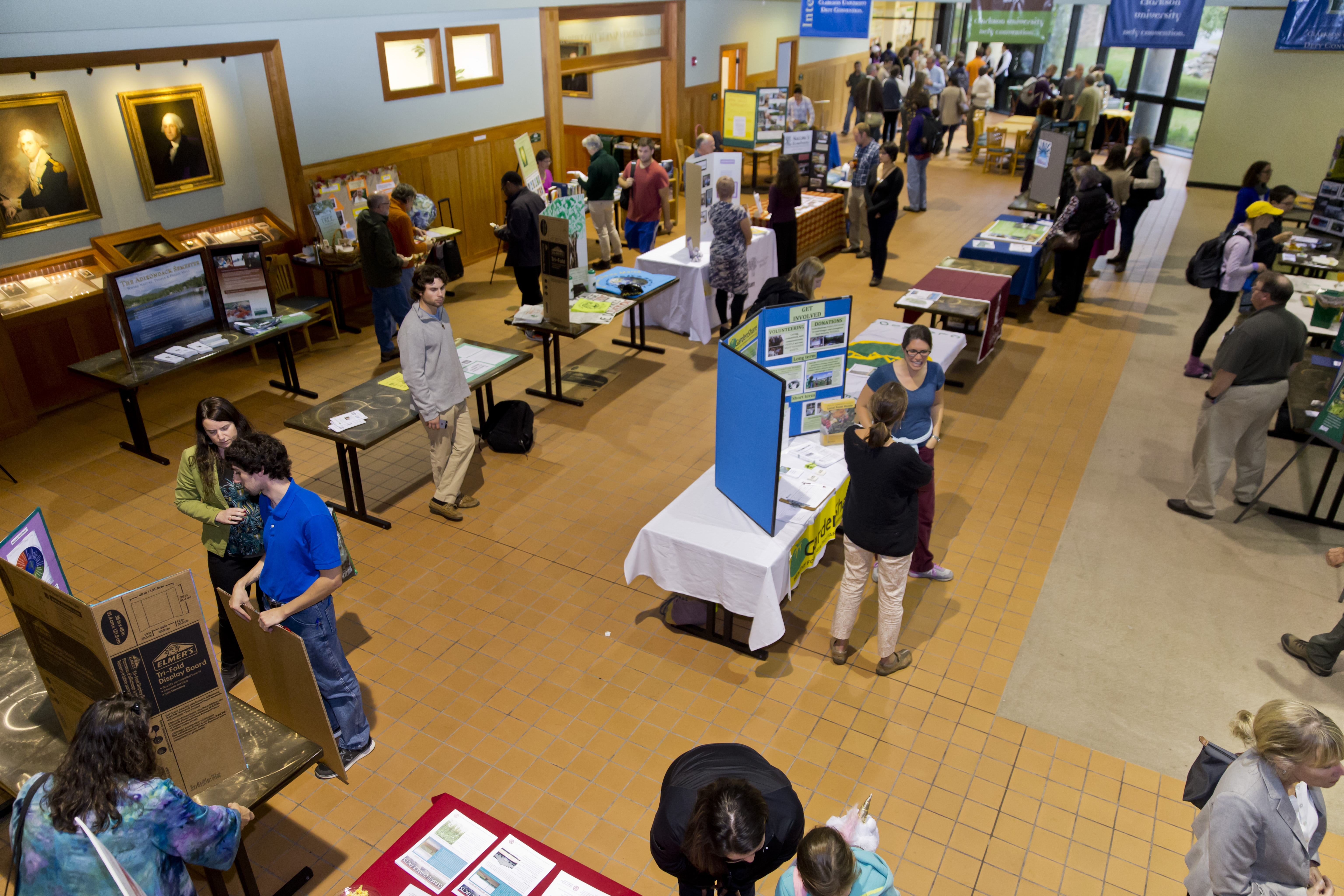 An overhead view of several students set up with poster presentations at tables for viewing by attendees.