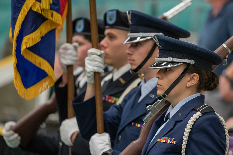 ROTC students standing at attention with flags