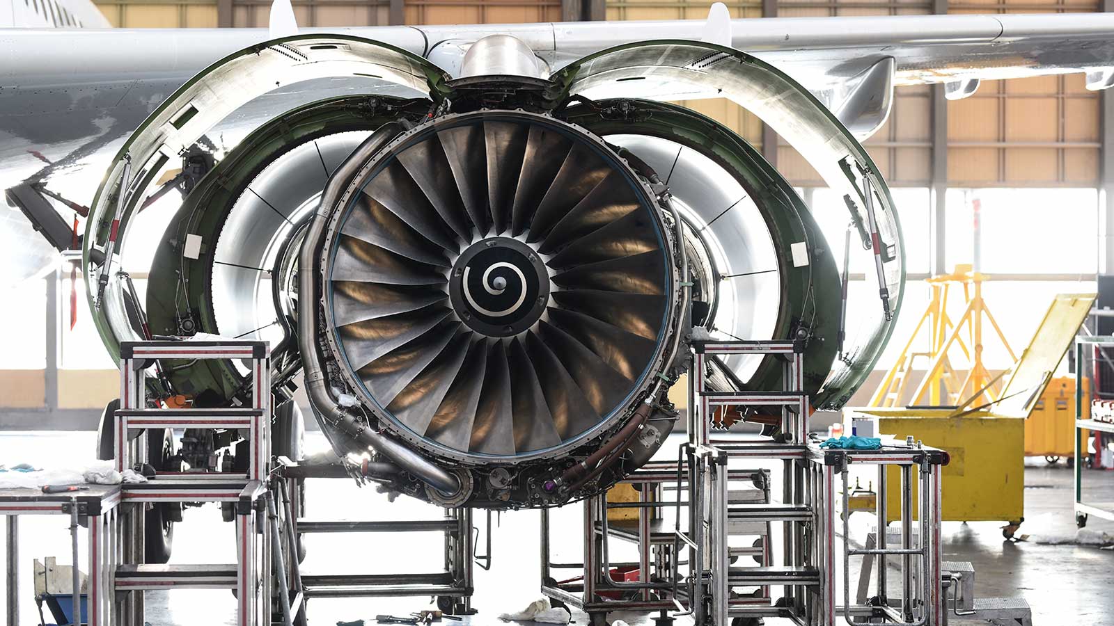 A jet engine being worked on in a large hangar