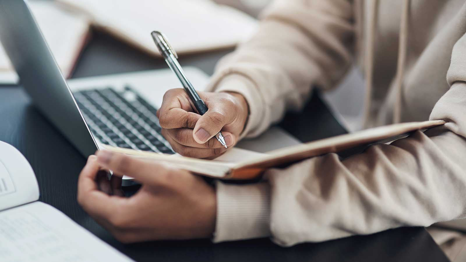 Person taking notes from laptop representing Business Studies program at Clarkson