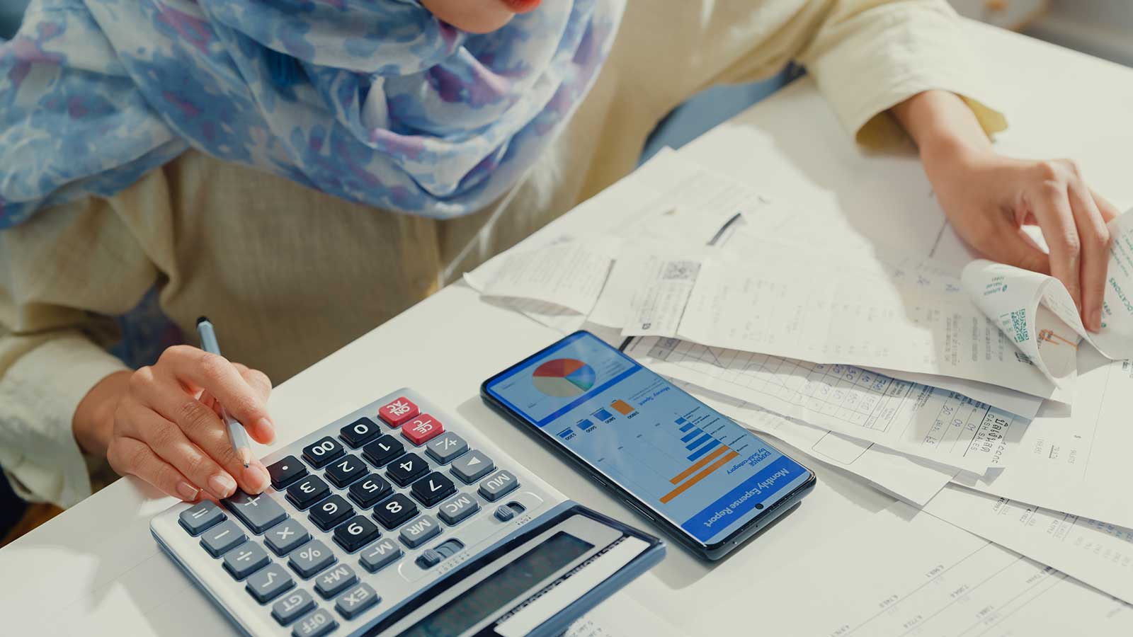 Person with receipts, phone, and calculator representing Finance program at Clarkson