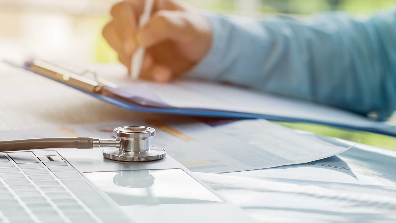 Stethoscope in desk with hands in background