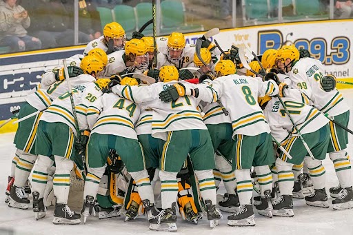 Clarkson men's hockey players huddle in a hug during a game on the ice