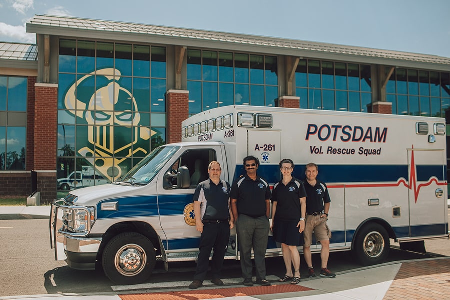 Potsdam EMS workers stand in front of their ambulance