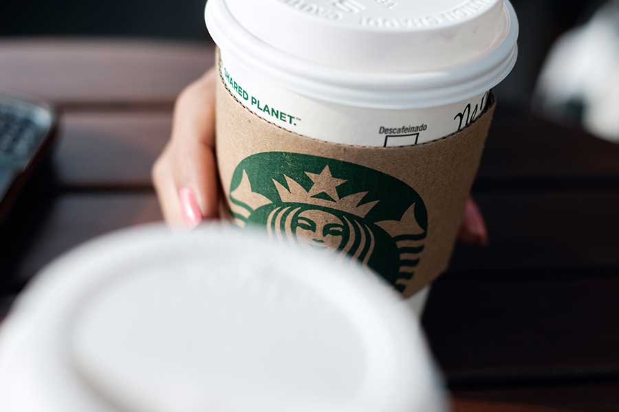 Individual holding a Starbucks coffee cup