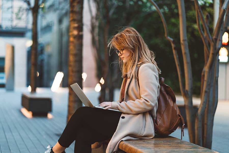 woman using a laptop on a city street