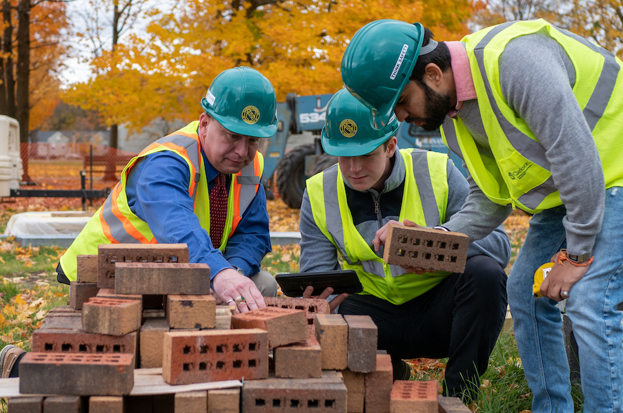 Construction Engineering Management class at Clarkson University; professor and students standing at brick pile.