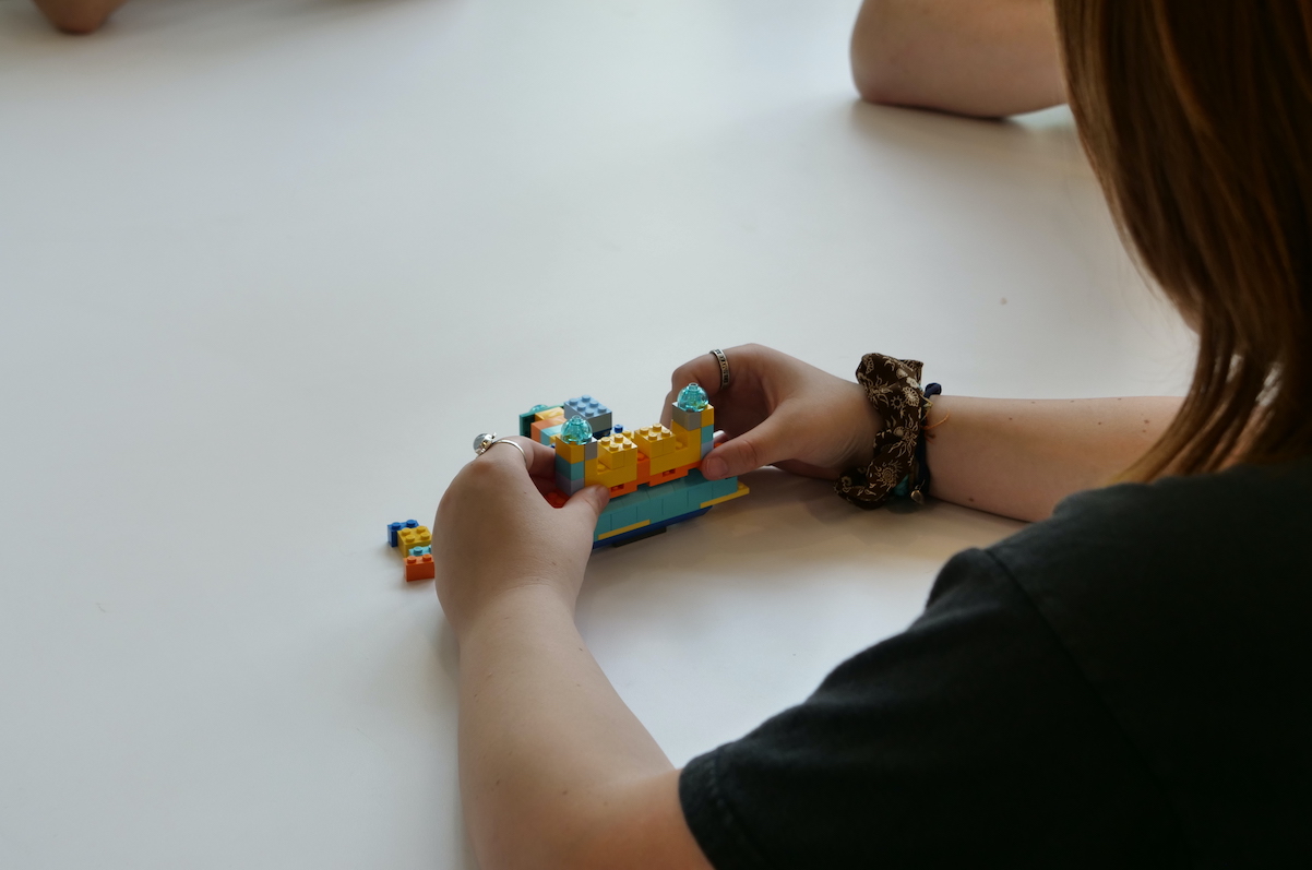 Female student's hands holding Lego structure.