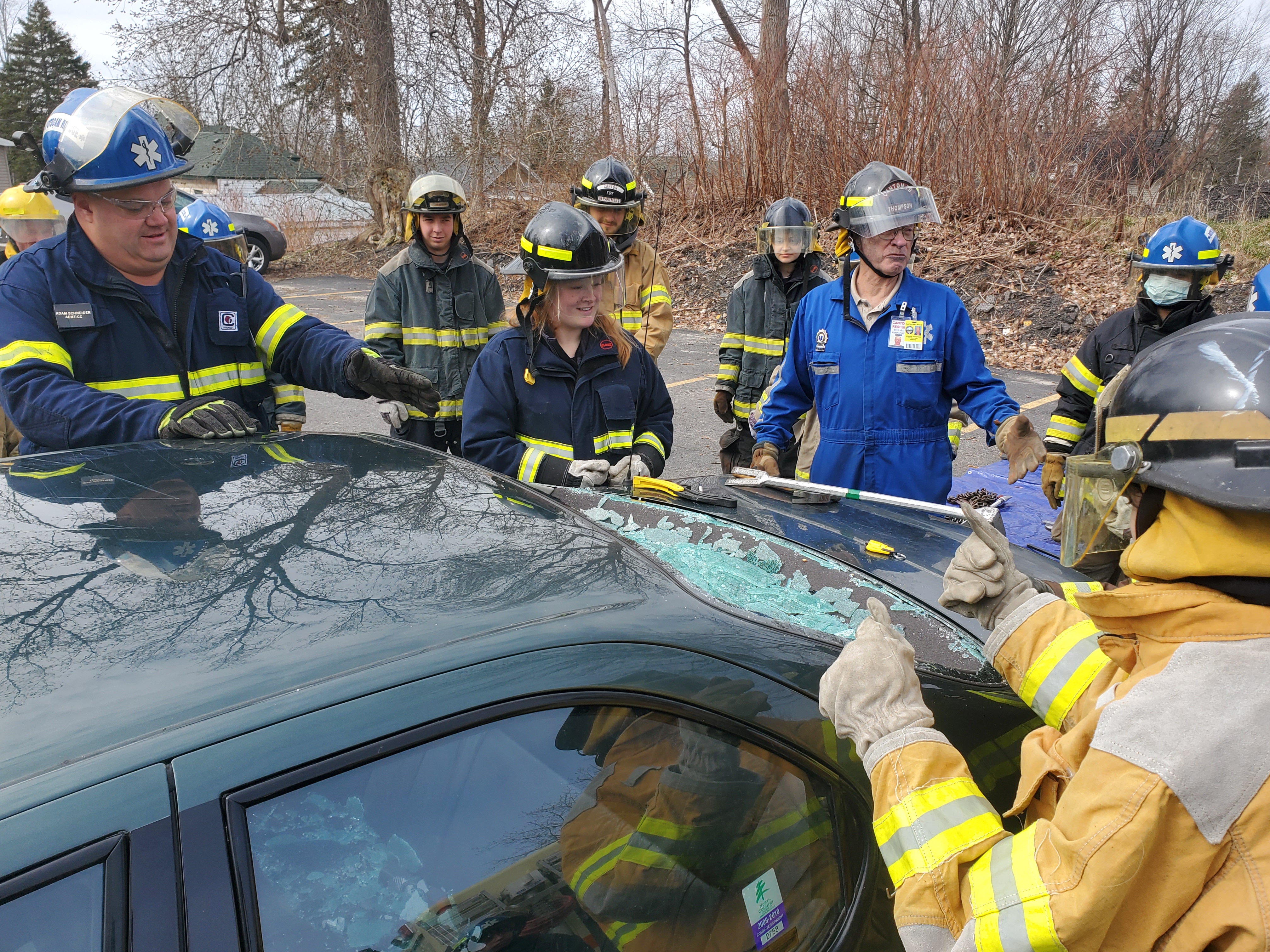 Firefighters and EMS professionals work on a broken car windshield