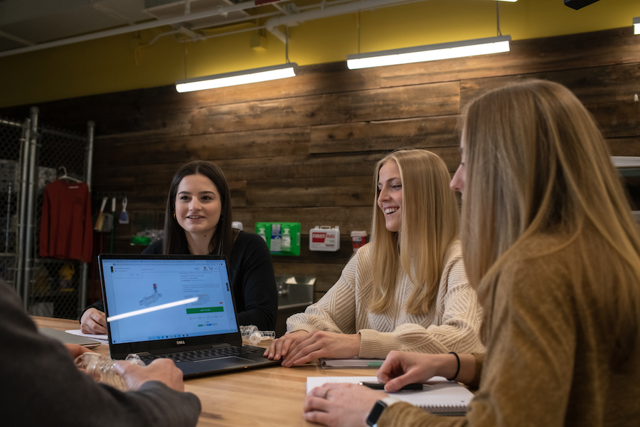 Three female students collaborating around a desk.