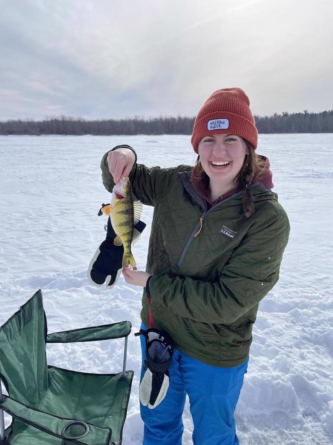 a women holding a fish up in the snow