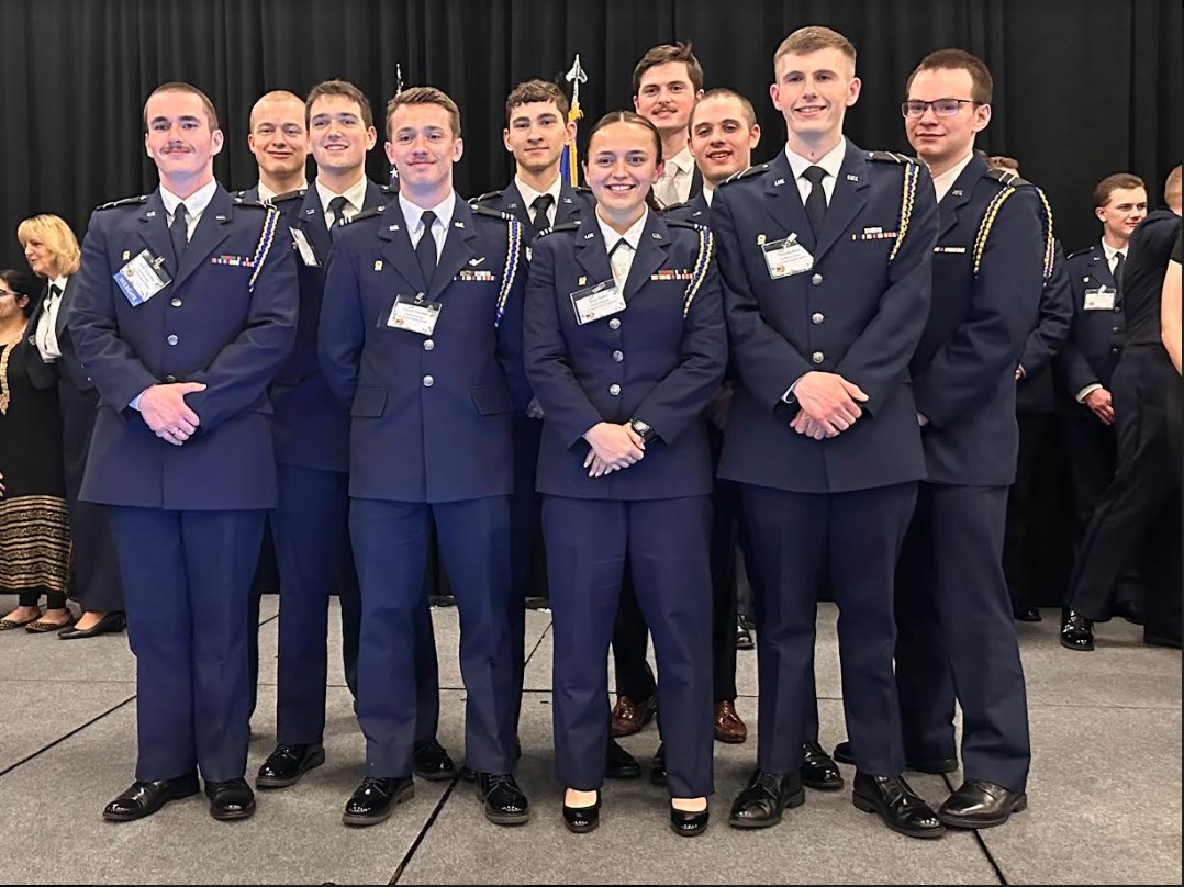 Ten Air Force ROTC students in dress blues posing for a group photo on a stage