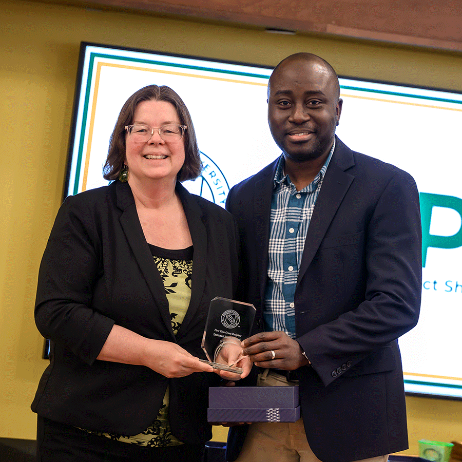 Dr. Asante-Asamani from the department of mathematics receives an award from Clarkson President Michelle B. Larson