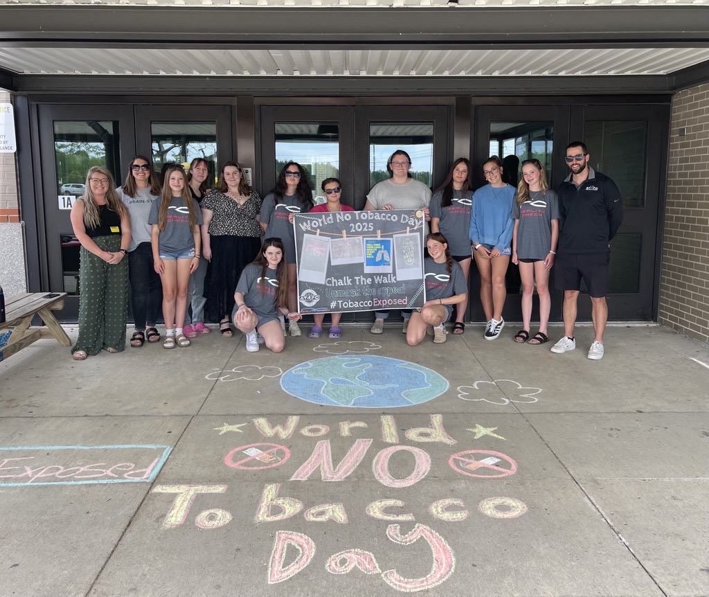 Students pose for a photo in front of their school doors, with No Tobacco chalk drawings on the sidewalk in front of them