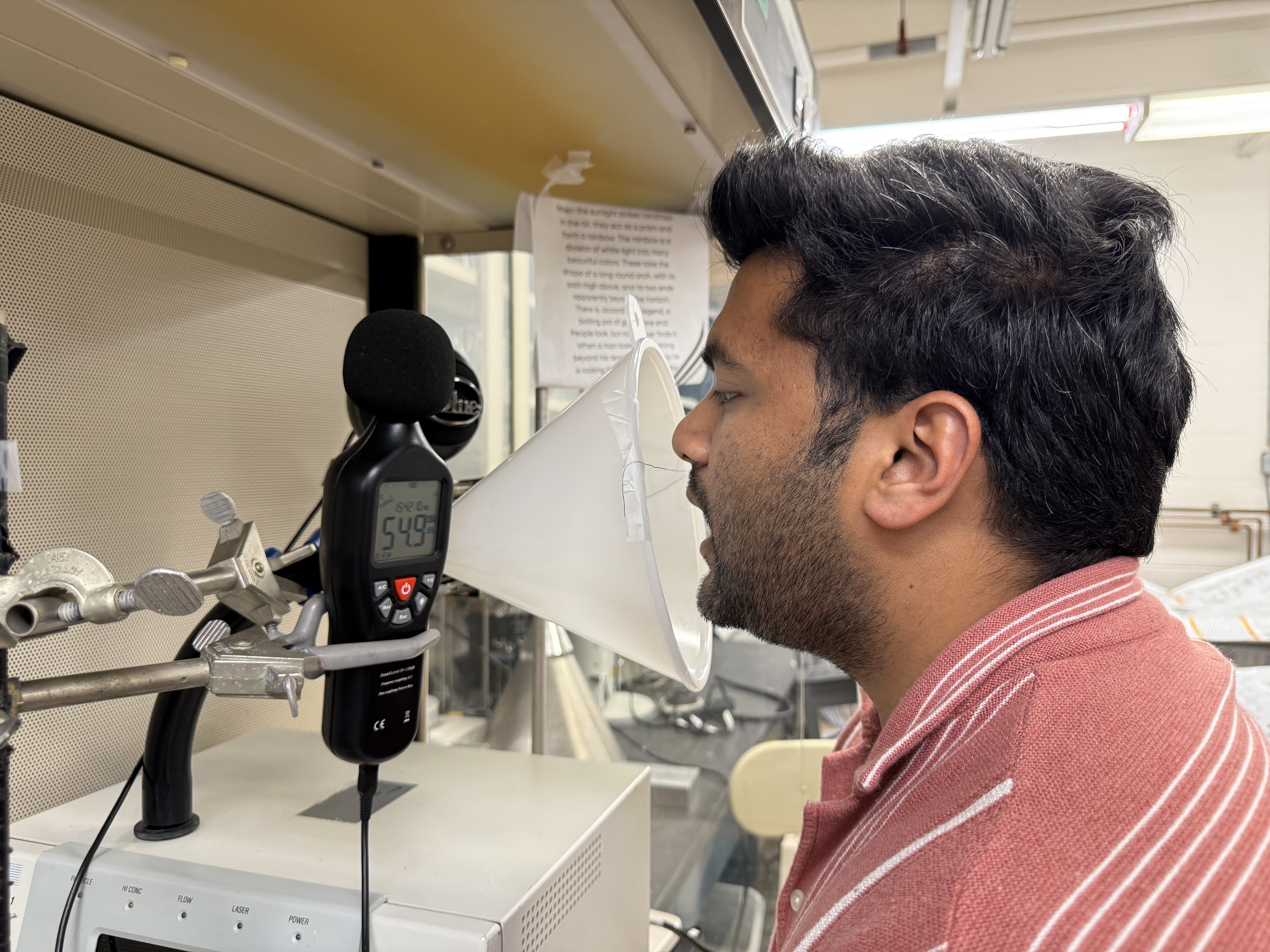 A man with his mouth open faces a conical device used to measure aerosol particles