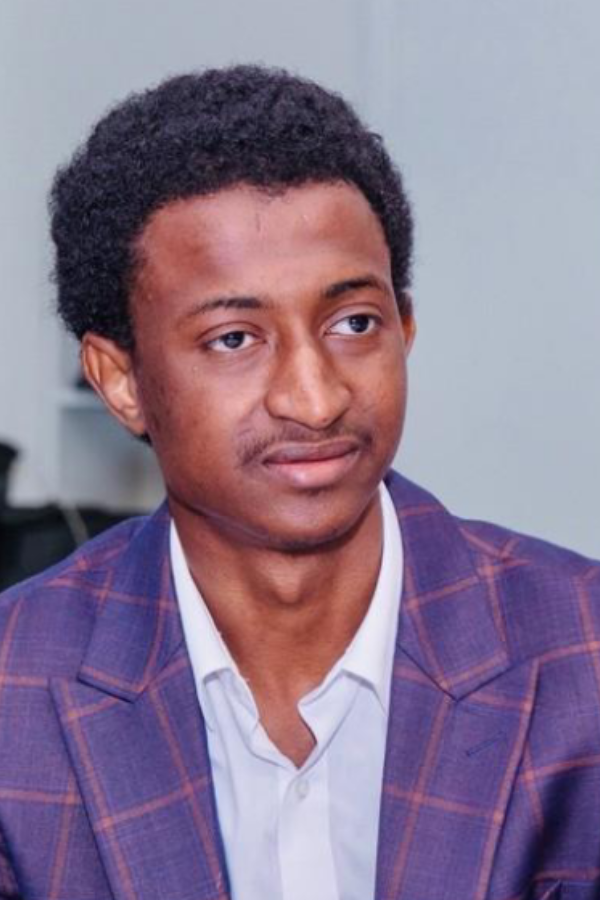 Headshot photo of Ousmane Diallo looking dapper in a plaid purple suit