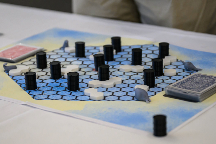 A board game with blue hexagon tiles and white and black pieces and decks of cards on each side. 