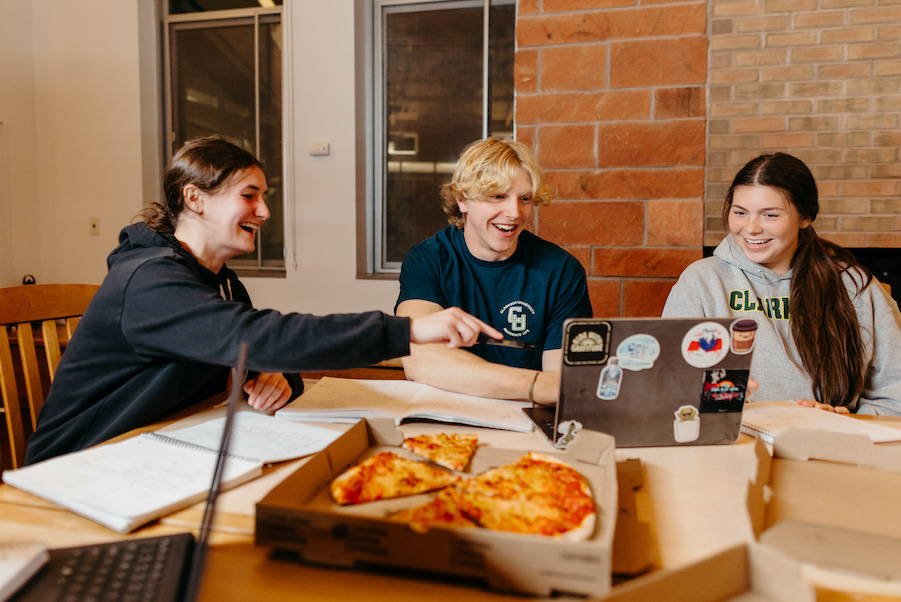 Clarkson University students sit around a shared pizza.