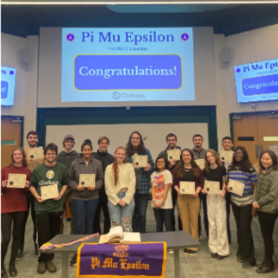 The Pi Mu Epsilon Induction ceremony with members holding their certificates with a giant "Congratulations!" on the projector screen behind them.