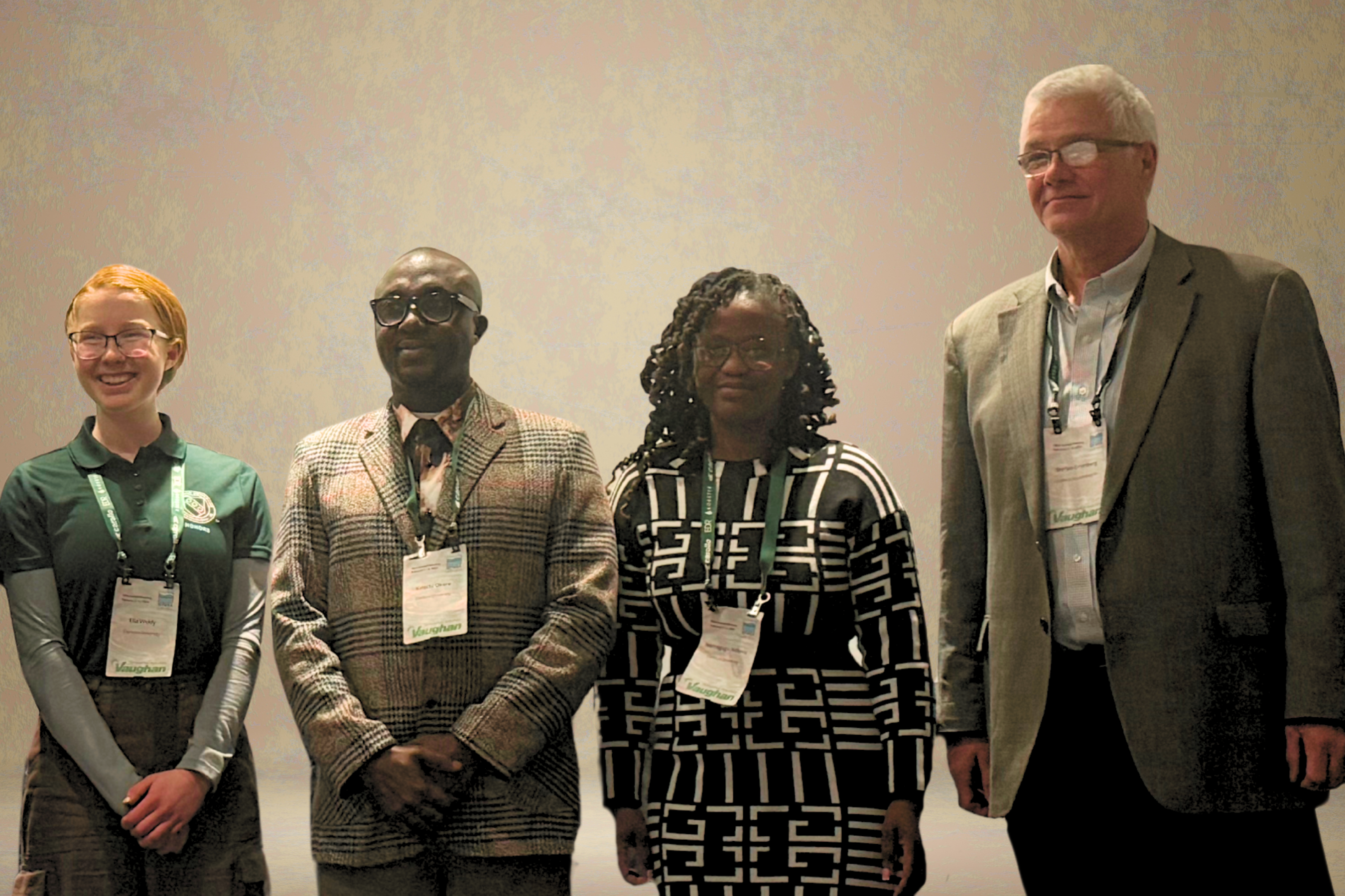 Three students pose for a photo with their professor