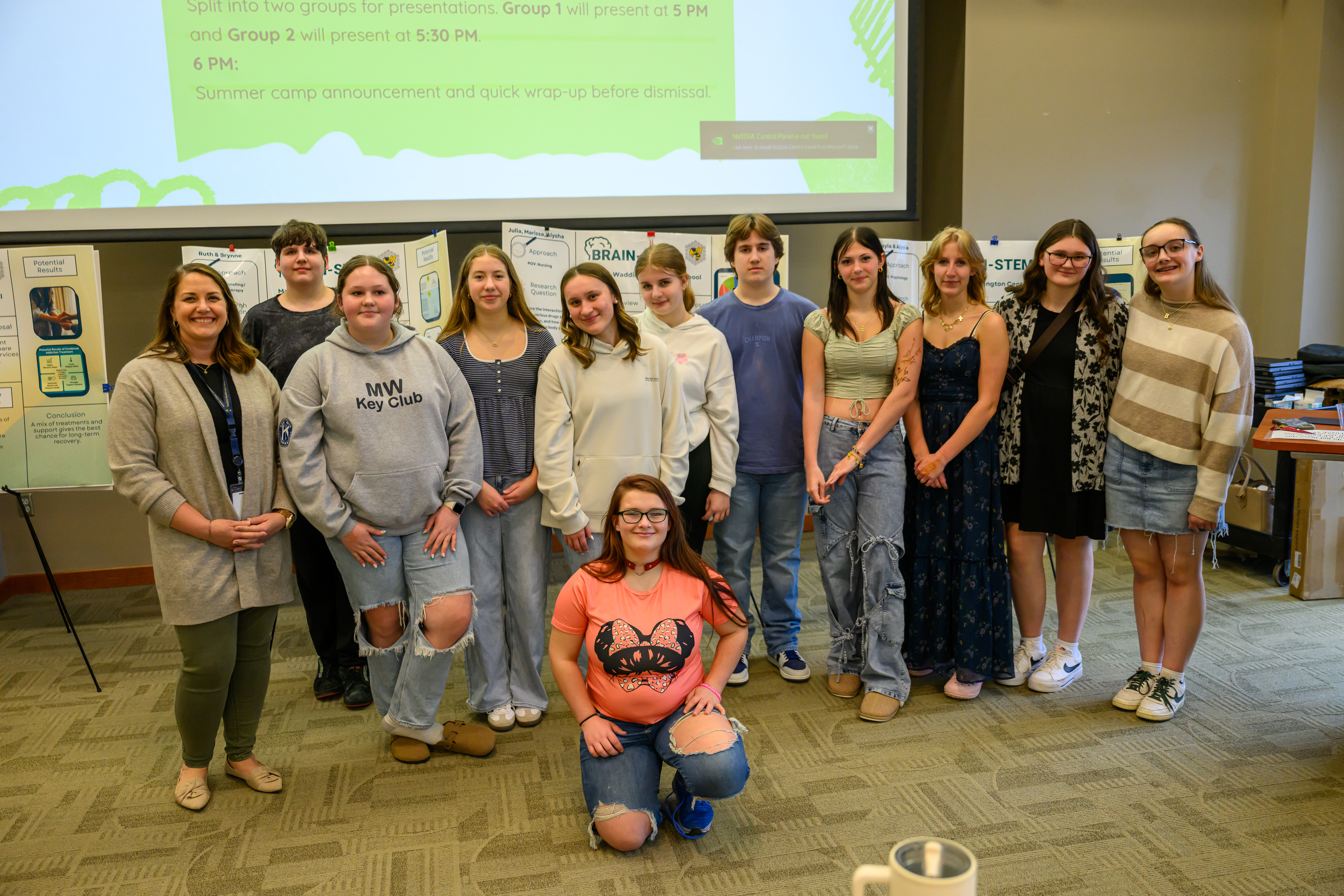 Several high school aged students pose in front of project posters in a conference space at Clarkson University