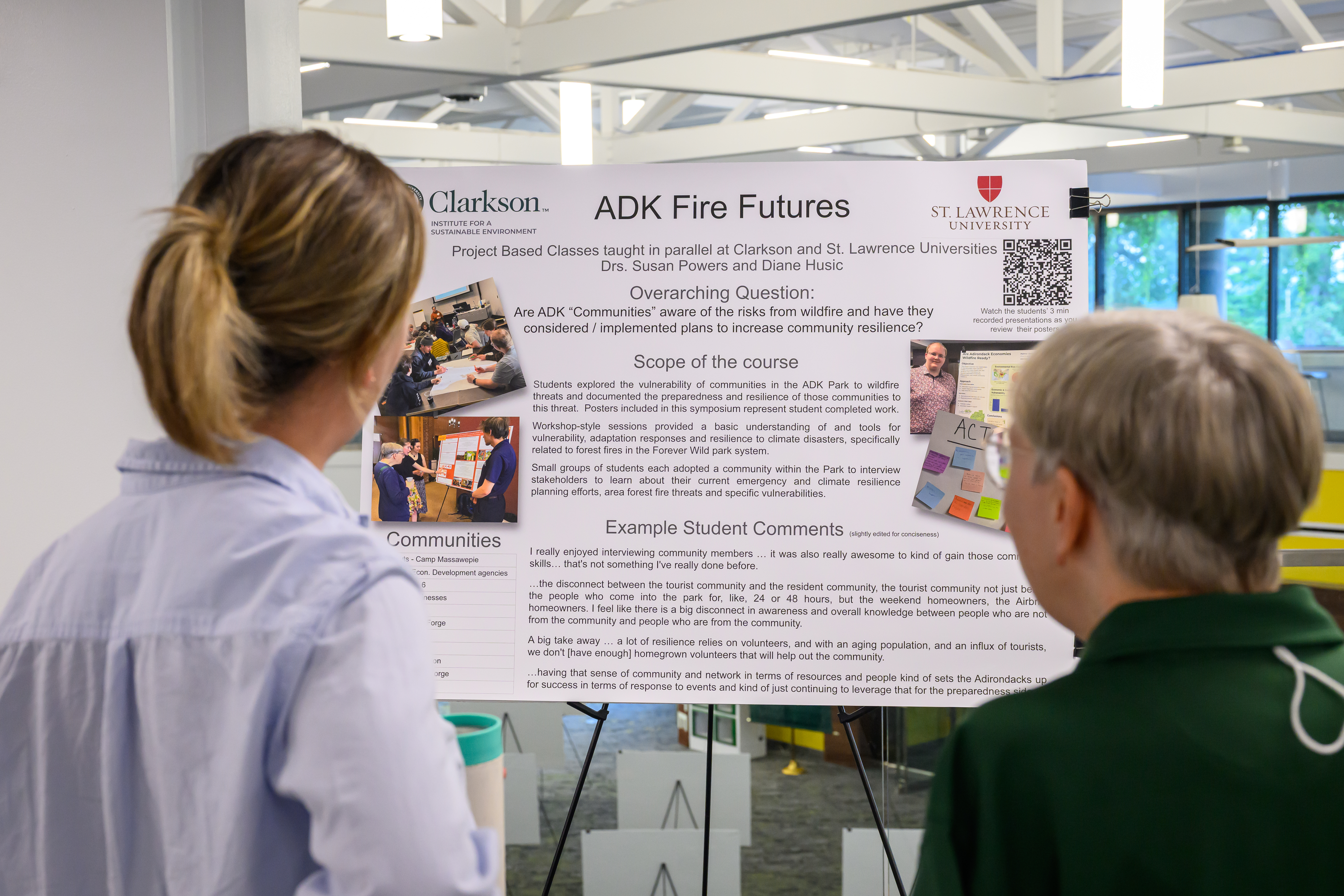 Two people view a research poster titled “ADK Fire Futures” about wildfire risk, community preparedness and resilience in the Adirondack Park.